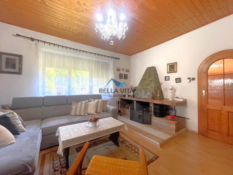 Obývacia izba v rodinnom dome s podlahou s dreveným dekorom a krbom.