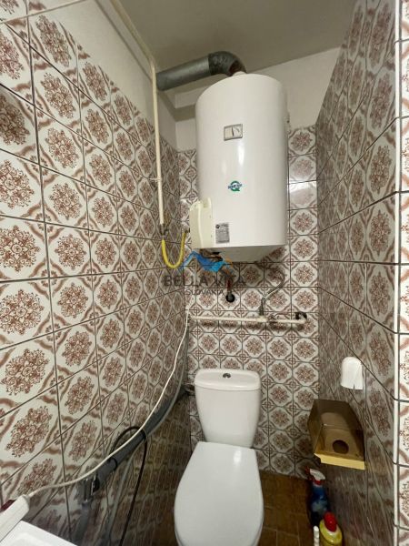 Toaleta v rodinnom dome s vintage obkladmi a bojlerom na stene.