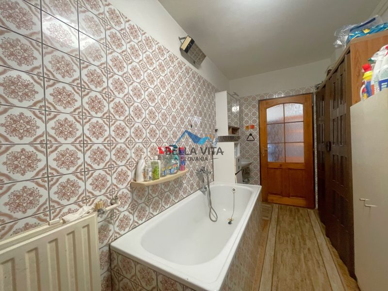 Kúpeľňa v rodinnom dome s vaňou, obkladačkami a podlahou s dreveným dekorom.