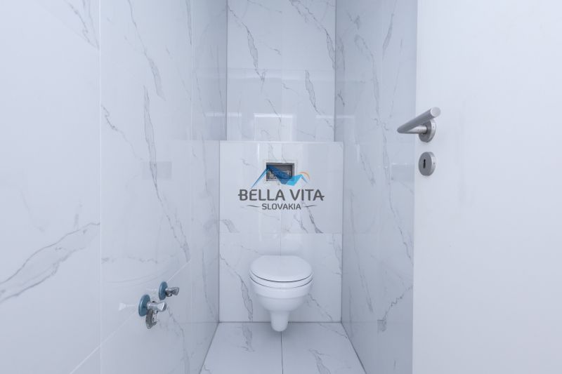 Kúpeľňa v rodinnom dome s bielymi kachličkami imitujúcimi mramor.