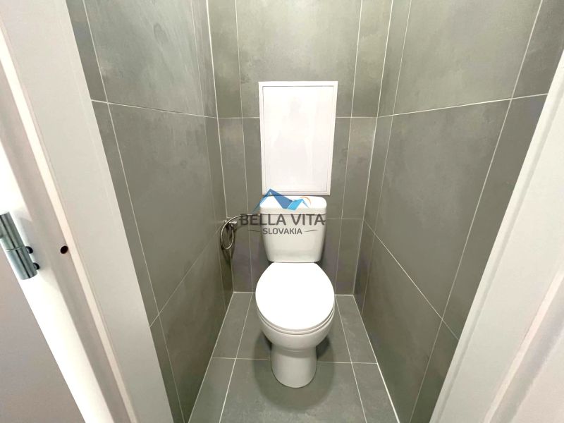 Toaleta s šedými obkladmi v 2-izbovom byte.