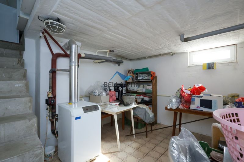 Technická miestnosť v rodinnom dome s kotlom a skladovacími policami.