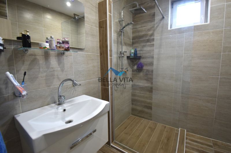 Kúpeľňa v rodinnom dome s umývadlom a sprchovacím kútom s dreveným dekorom.