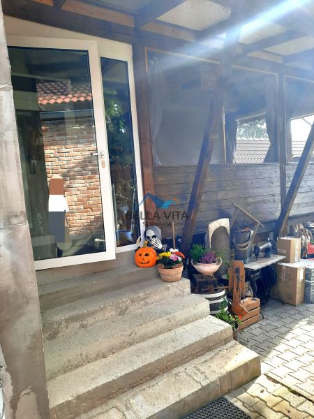 Schody vedúce k dverám rodinného domu so sezónnymi dekoráciami a kvetmi.