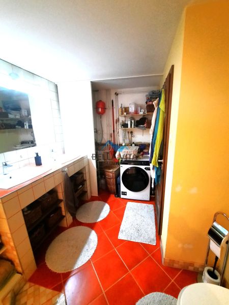 Kúpeľňa v rodinnom dome s oranžovou podlahou a práčkou.