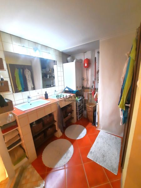 Kúpeľňa v rodinnom dome s kotlom, zrkadlom a oranžovými dlaždicami.