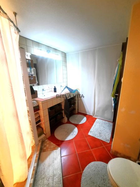 Kúpeľňa v rodinnom dome s červenou dlažbou, umývadlom a sprchovým kútom.